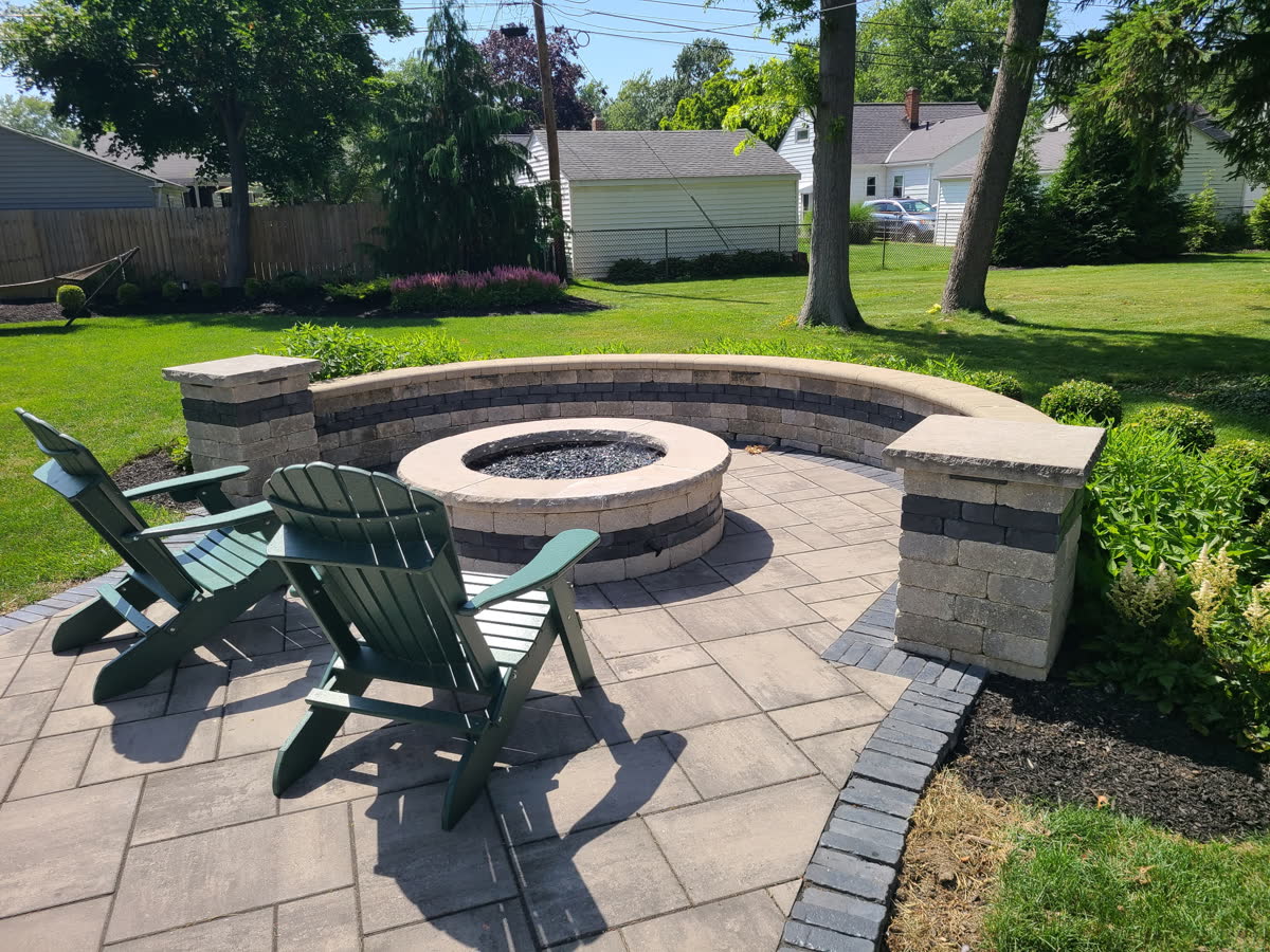 Backyard paver patio with stone fire pit and seating, landscaping by Brunner Landscape in Northeast Ohio