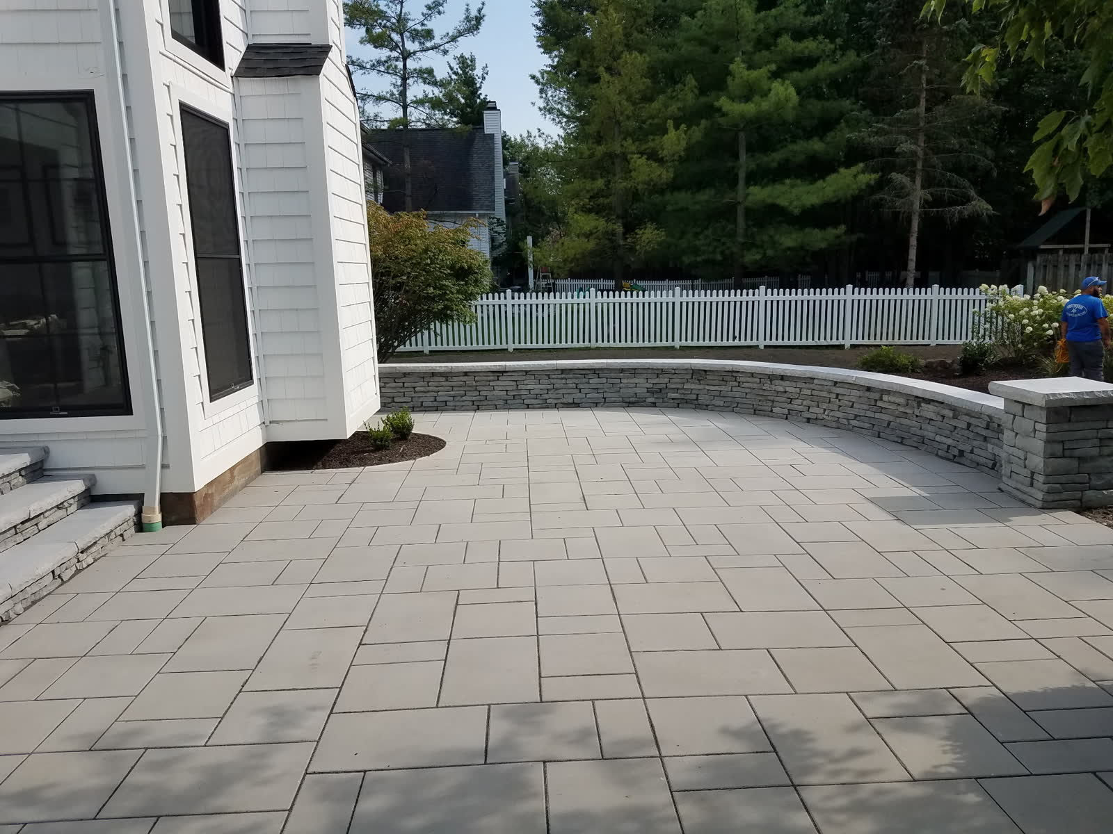 Curved paver patio with natural stone seat wall installed by Brunner Landscape in Northeast Ohio
